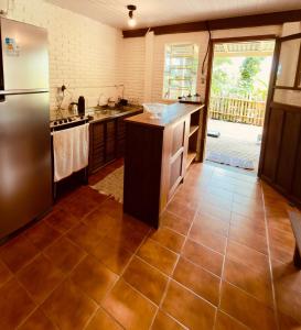 a kitchen with a stainless steel refrigerator and a tile floor at Cabana Rosa na mata in Imbituba