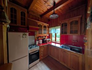 a kitchen with wooden cabinets and a white refrigerator at Dowcień in Burdeniszki
