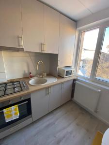 a kitchen with white cabinets and a sink and a window at Central Nest in Tecuci