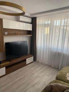 a living room with a flat screen tv and curtains at Central Nest in Tecuci