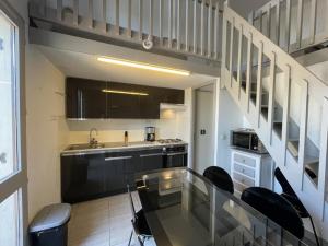 eine Küche mit einem Glastisch und einigen Stühlen in der Unterkunft Appartement T2 Mezzanine avec Terrasse Proche Lac - Animaux Acceptés ! - FR-1-379-27 in Vieux-Boucau-les-Bains