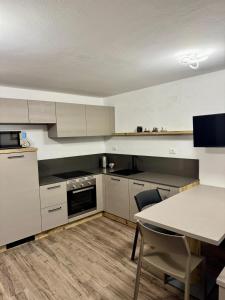 una cucina con mobili bianchi e un tavolo con sedie di Appartamento della Nonna a Sùtrio