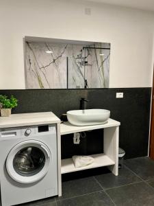 a bathroom with a washing machine and a sink at Appartamento della Nonna in Sùtrio +6 photos