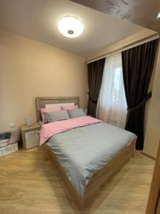 una camera da letto con un letto con lenzuola rosa e una finestra di La Montana 3 a Zlatibor