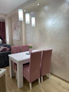 una sala da pranzo con tavolo bianco e sedie rosa di La Montana 3 a Zlatibor Altre 3 foto