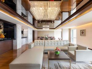 a living room with a large couch and a chandelier at Novotel Yangon Max in Yangon