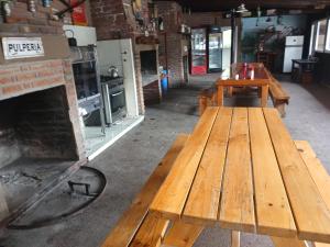 a wooden picnic table in a room with a fireplace at Altos de el bolson in El Bolsón +1 photo