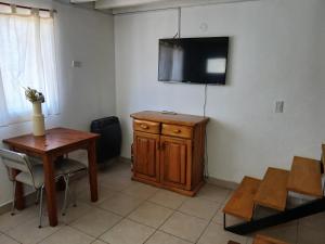 a room with a table and a television on a wall at Altos de el bolson in El Bolsón