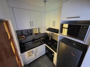 une petite cuisine avec des armoires blanches et des appareils électroménagers noirs dans l'établissement Casa-Pel Guest Wing, à Palatswe