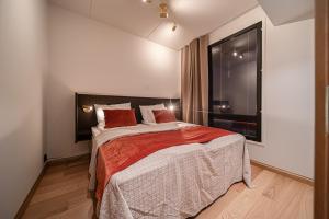 a bedroom with a bed with red pillows and a window at Levillas Lingonberry D26 in Levi