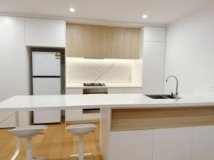 a white kitchen with a sink and a counter at Prospect Box Hill - Magnificent View 2B1B in Box Hill