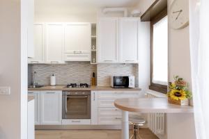 a kitchen with white cabinets and a table and a clock at Smart Flat - Easy Milan Link in Cinisello Balsamo