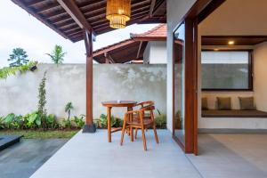 een terras met een houten tafel en stoelen bij Akar Villa in Ubud