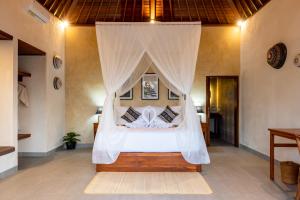 een slaapkamer met een hemelbed bij Akar Villa in Ubud