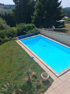 een groot blauw zwembad in een tuin bij Chambres d'hôtes in Échandelys