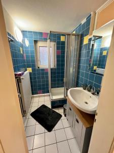 een blauwe betegelde badkamer met een wastafel en een douche bij Ferienwohnung auf dem Berg in Bad Bentheim