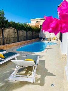 a swimming pool with two lounge chairs and a swimming pool at Magawish Hurghada Studio 7 in Hurghada