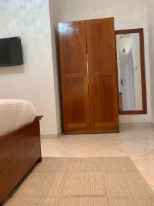 ein Schlafzimmer mit einem Holzschrank und einem Spiegel in der Unterkunft Haven Seven Property - 1 bedroom, 2 bedroom, 3 bedroom Executive options in Takoradi
