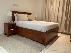 ein Schlafzimmer mit einem großen Bett mit Holzrahmen in der Unterkunft Haven Seven Property - 1 bedroom, 2 bedroom, 3 bedroom Executive options in Takoradi
