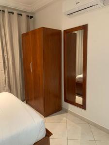 ein Schlafzimmer mit einem Holzschrank und einem Spiegel in der Unterkunft Haven Seven Property - 1 bedroom, 2 bedroom, 3 bedroom Executive options in Takoradi + 30 Fotos