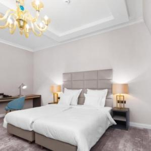 een slaapkamer met een groot wit bed en een kroonluchter bij Hotel grand Park in Szczecin