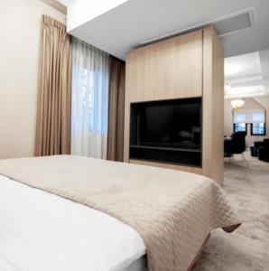 een slaapkamer met een bed en een flatscreen-tv bij Hotel grand Park in Szczecin