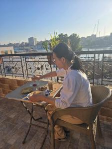 een vrouw aan een tafel op een balkon bij Bakar Nubian Guest House in Aswan