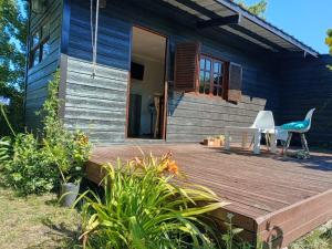 a blue house with a wooden deck and a chair at Casa Nina in Camet Norte