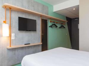 een slaapkamer met een bed en een tv aan de muur bij ibis budget Senlis in Senlis