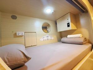 a small room with a bed and a mirror at Coller Chinatown in Singapore