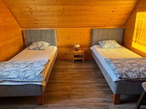 two beds in a room with wooden walls at Domek Karkonosze in Wojcieszyce