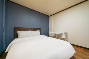ein Schlafzimmer mit einem weißen Bett und einer blauen Wand in der Unterkunft 귀빈모텔 in Donghae