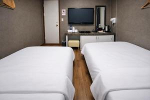 2 Betten in einem Zimmer mit einem Schreibtisch und einem TV in der Unterkunft 귀빈모텔 in Donghae