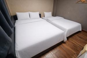 zwei Betten in einem Zimmer mit weißen Laken in der Unterkunft 귀빈모텔 in Donghae + 2 Fotos