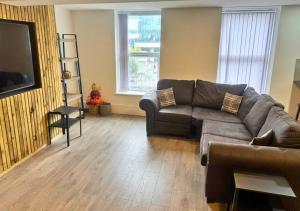 een woonkamer met een bank en een flatscreen-tv bij Williamson Suites - Apartment 1 in Liverpool