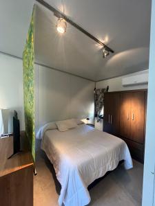 een slaapkamer met een groot wit bed en houten kasten bij Monoambiente de playa in José Ignacio +6 foto's