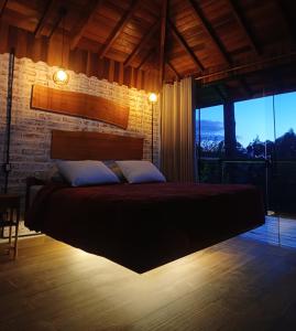 un lit dans une chambre avec une grande fenêtre dans l'établissement Chalés Descanso na Serra, à Monte Verde
