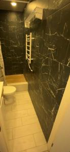 a bathroom with a toilet and a black marble wall at TopApartment 1 in Sumy