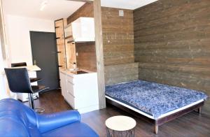 a small room with a bed and a blue couch at Studio, centre La Bresse in La Bresse