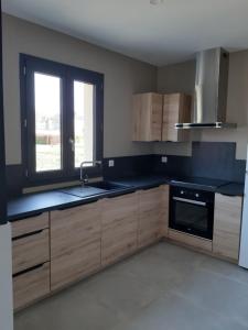 a kitchen with wooden cabinets and a sink and a window at Location proche Sarlat in Prats-de-Carlux