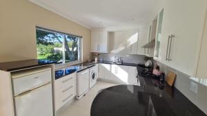 a large kitchen with white cabinets and a window at Flanders South Cottage in Gqeberha +9 photos