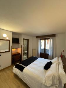 een slaapkamer met een groot wit bed en een raam bij Hotel Alle Tre Baite in Santa Caterina Valfurva