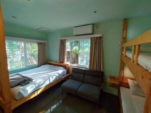 una camera da letto con un letto, una sedia e due finestre di Nemurupa Garden Hostel & Yoga a Narita