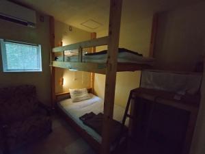 a bedroom with bunk beds in a room with a television at Nemurupa Garden Hostel and Yoga near Narita Airport 15 min Shuttle in Narita