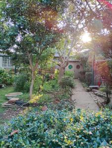 un giardino con alberi e fiori e un marciapiede di Nemurupa Garden Hostel & Yoga a Narita