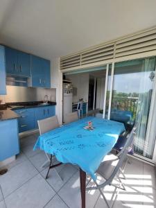 a kitchen and dining room with a blue table and chairs at Le CATALEYHA in Le Moule