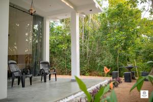 a porch with chairs and a table and trees at Willow Waters in Galle