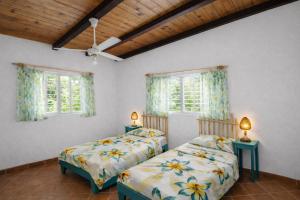 two beds in a room with two windows at Casa los Mangos Private pool 150 m from the beach in Las Galeras