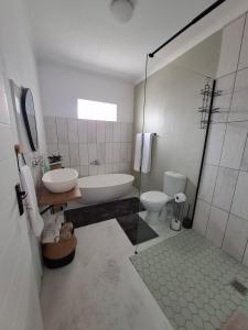 a bathroom with a tub and a sink and a toilet at Embrace This Planet Self-Catering Accommodation in Fisherhaven +8 photos