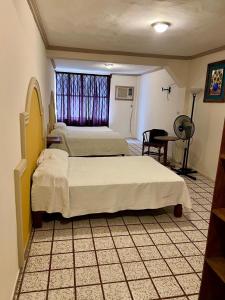 ein Schlafzimmer mit zwei Betten und einem Schreibtisch und einem Fenster in der Unterkunft Hotel y Restaurant Real Plaza Jacona in Ciudad Valles